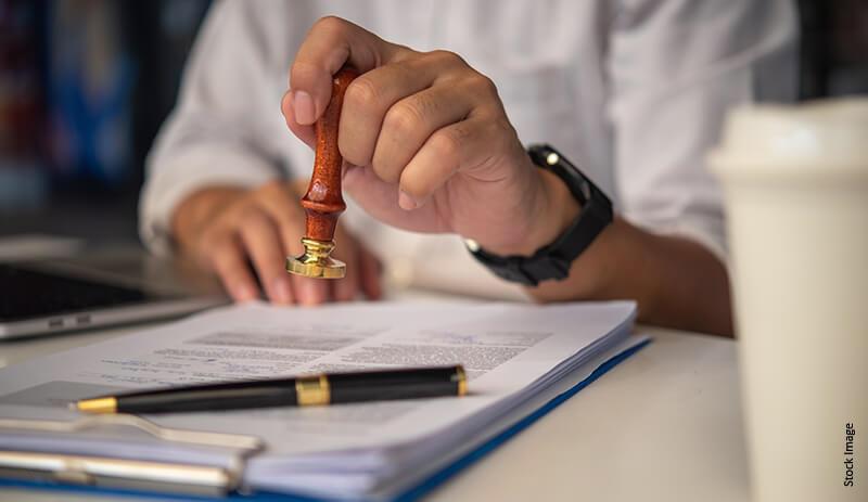 agent tenant un tampon pr&ecirc;t &agrave; estampiller des documents